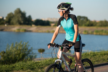 Woman on bike at the lake water background in the park