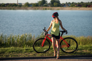 Fototapeta na wymiar Woman on bike at the lake water background in the park