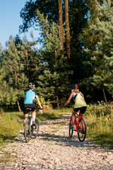 Two women friends riding bikes offroad at the forest