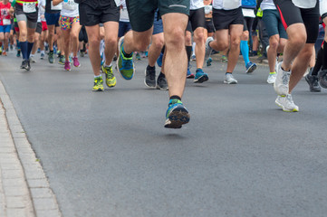 Legs group runners running on asphalt road. Selective focus.