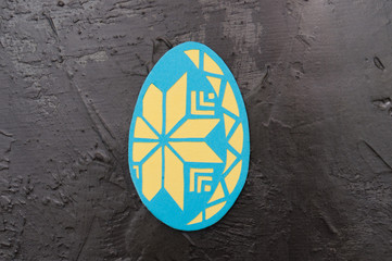 Handmade magnet in the shape of an Easter egg on a dark gray concrete background, Ukrainian...