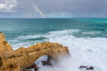 Beautiful view of the Arch rock along the Great Ocean Road, Australia, with a rainbow in the background