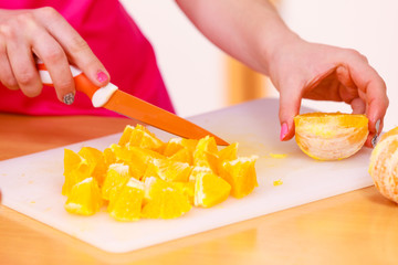 Woman housewife in kitchen cutting orange fruits