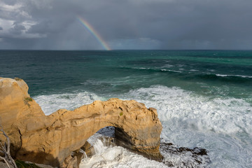 Beautiful view of the Arch rock along the Great Ocean Road, Australia, with a rainbow in the background
