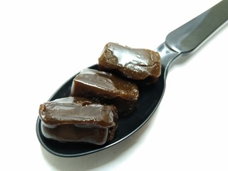 A picture of coffee flavour candy's on a black spoon