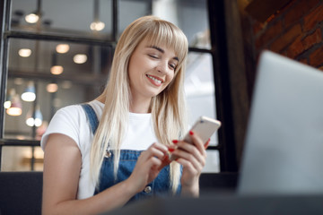 Young girl at cafe drinking coffee and using mobile phone. Online shopping
