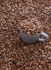 coffee beans in dark cup on mixed coffee beans background
