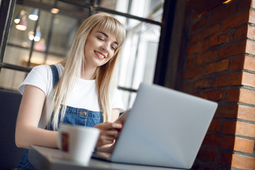 Young girl at cafe drinking coffee and using mobile phone. Online shopping