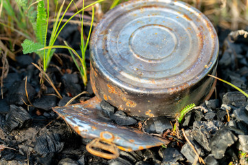 garbage after people in nature, fire and rusty cans closeup