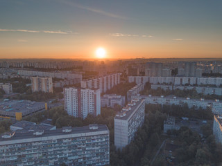 Aerial view of the city district with tall residential buildings, roofs, roads and highways, park zones and yards with green trees. Sunrise over summer urban landscape. Moscow city, Russia