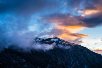 Fototapeta na wymiar Montenegro, Snow covered peak of durmitor mountains hidden by fog and glowing red clouds in magical dawning atmosphere at sunset on summit of mount curevac in national park near zabljak