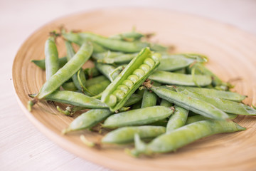 Green peas in white bowl on wooden background, top view.