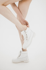 Girl model with long legs on white backgorund shot in studio putting on a white boot