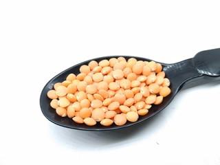 A picture of red lentil on a black spoon