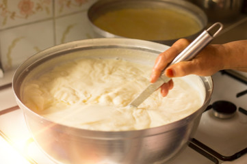 Hands of senior woman who is making homemade yoghurt ( yogurt ) with selective focus. Fermentation of yoghurt with blurred background.