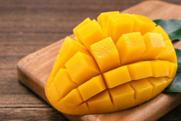 Fresh Mango - Juicy chopped mango cubes on wooden cutting board and rustic timber background. Tropical summer concept. Close up, macro, copy space.