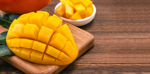 Fresh Mango - Juicy chopped mango cubes on wooden cutting board and rustic timber background. Tropical summer concept. Close up, macro, copy space.