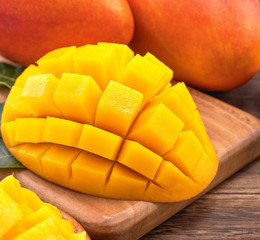 Fresh Mango - Juicy chopped mango cubes on wooden cutting board and rustic timber background. Tropical summer concept. Close up, macro, copy space.