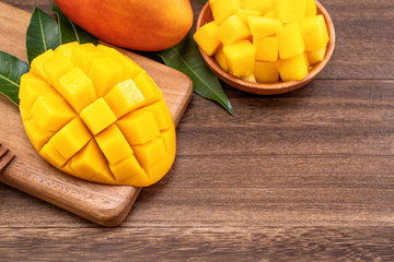 Fresh Mango - Juicy chopped mango cubes on wooden cutting board and rustic timber background. Tropical summer concept. Close up, macro, copy space.
