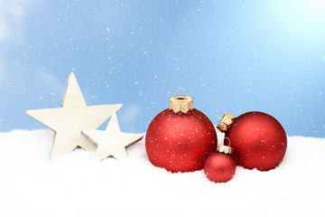 red christmas baubles and wooden star lying in snow © Caro