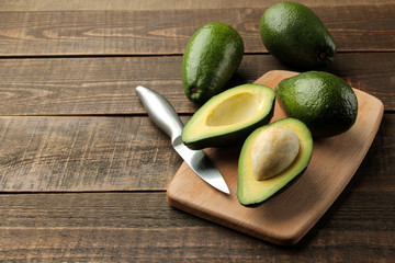 Fresh ripe tasty avocado on a cutting board on a brown wooden background. tropical fruit
