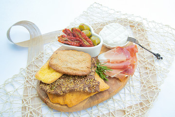 still life crispy pizza, prosciutto, cheese ,green olives, dried tomatoes on a wooden plate.