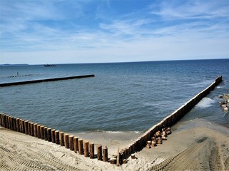 Blue sea with wooden breakwaters.