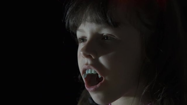 Child on the night of Halloween. Little girl with fangs in the dark. Halloween child.