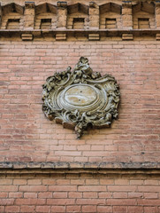 A fragment of the old wall with a floral Cartouche (cartouch), detail of facade, architecture detail. Oval design with a slightly convex surface, edged with ornamental scrollwork and plant ornament. 