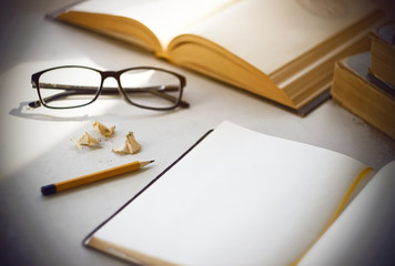 Bright workplace scientist - old shabby books, a diary with a bookmark, glasses in black, yellow pencil and shavings from his sharpening.