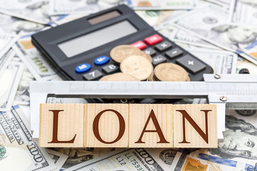 Bank loan concept. Wooden cubes with word "loan", vernier caliper, money and calculator.