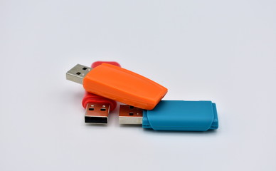 USB flash memory drives with colours, orange, blue and red, on a white background.