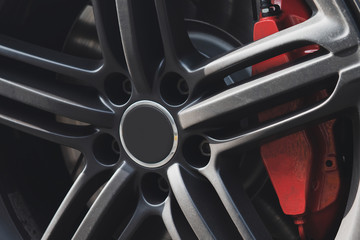 Gray metal car wheel with red brake support. Sport style steel rim. Closeup.