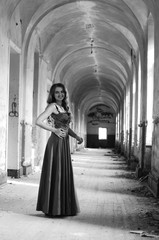 Naklejka premium Young beautiful short hair blonde woman in black climbing the stairs, black and white photo. Side view of elegant romantic mysterious lady with movie star look in interior with bricks walls