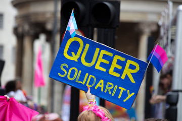 A person holding a queer solidarity banner at a gay pride event
