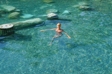 Beautiful woman bathing in a natural thermal pool
