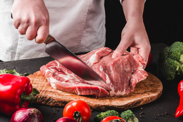 Chef Butcher cutting pork meat with knife on kitchen, cooking food