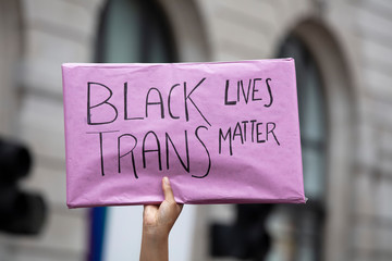 A person holding a black trans lives matter banner at a gay pride event