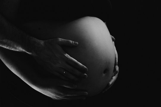 manos de padres sobre tripa de embarazada - blanco y negro