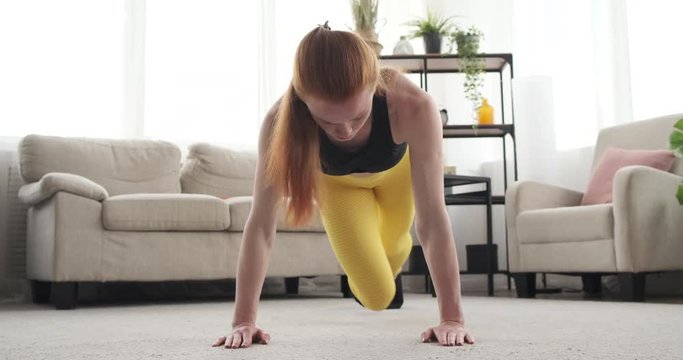 Sportswoman doing alternate knee to elbow plank exercise at home
