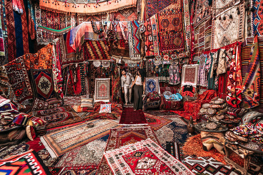 Couple travels the world. Man and woman in the store. Happy couple on vacation. Man and woman in the Eastern country. Gift shop. Persian shop. Tourists in store. Oriental carpet. Follow me