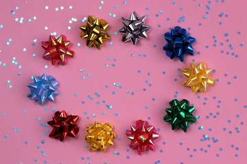 The texture of a lot of festive bows in the form of a star on a pink background in the shape of an oval