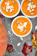 Cream of pumpkin soup or souffle on a gray background.  Thanksgiving Day. Diet vegetarian pupmkin soup puree. View from above, flat lay. Rustic.