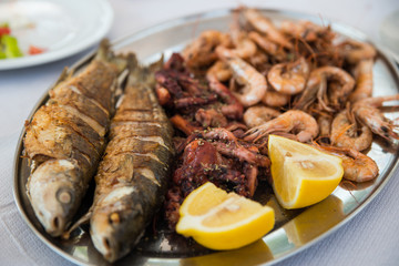 seafood dish. fried fish and shrimps with lemon slices. dinner on the sea coast