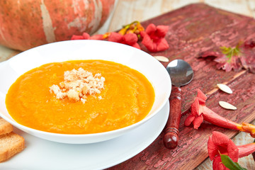 Cream of pumpkin soup on a white wooden background.