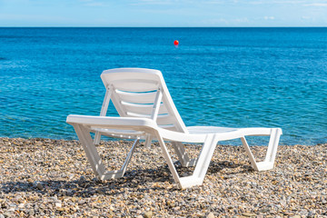 Empty white plastic chaise lounge on the background of the sea