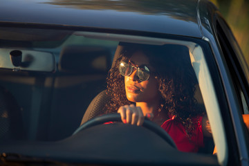Happy woman driver sitting in car salon at sunset