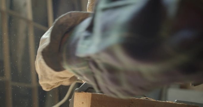 Close-up portrait of hands of senior carpenter drilling the wood at manufacture.