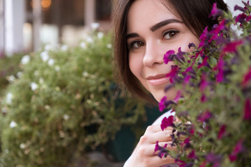 Naklejka premium Close up of brunette woman face in flowers. She smiling cheerfully. Copy space