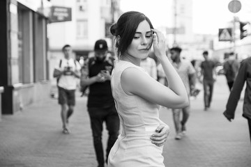 Brunette girl in grey smark casual dress walking in european city. She look sad. copy space